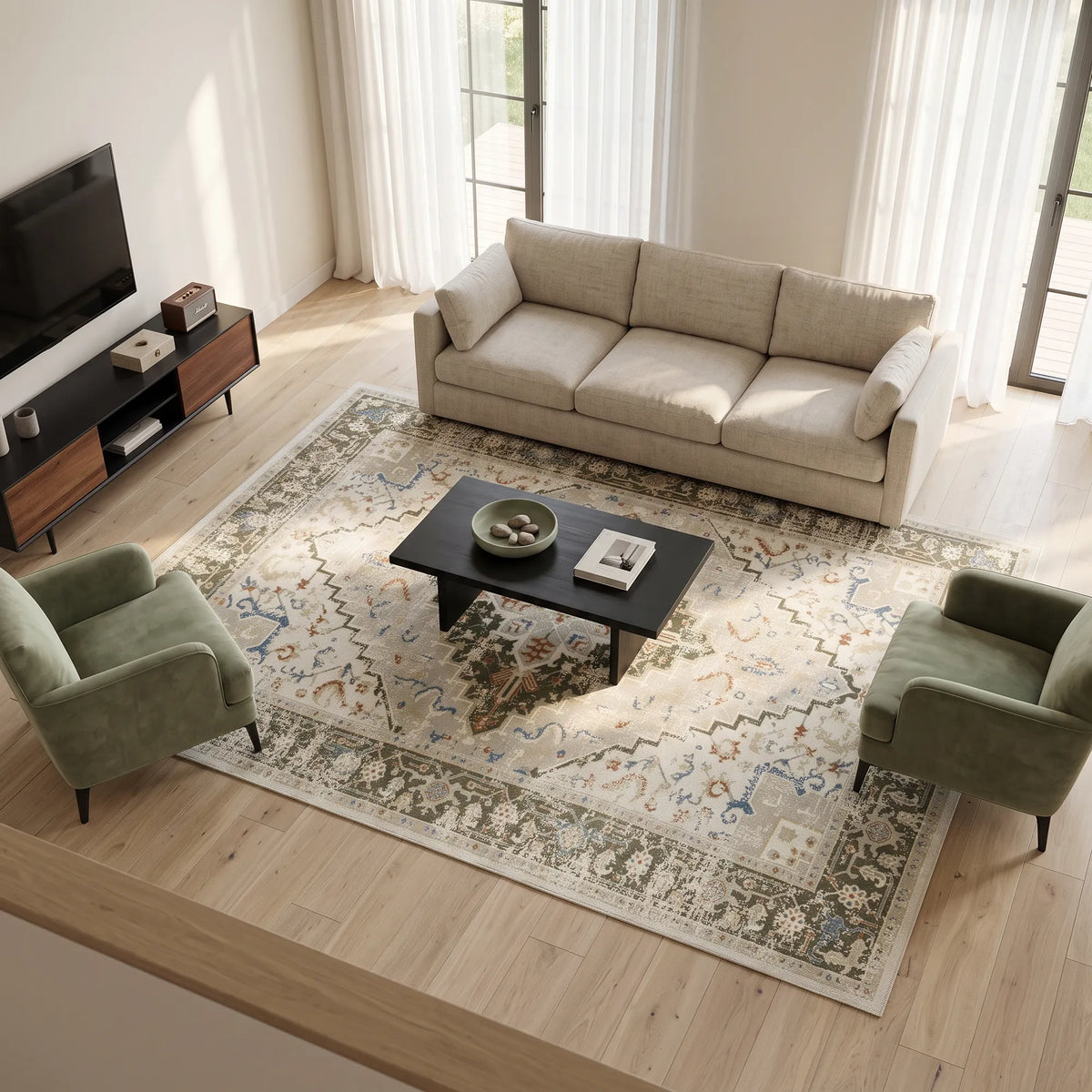 Eine stilvoll eingerichtete Wohnzimmeransicht mit einem großen gemusterten Teppich auf einem hellen Holzboden, einem beigefarbenen Sofa, zwei grünen Sesseln, einem schwarzen Couchtisch und einem Fernseher im Hintergrund.
