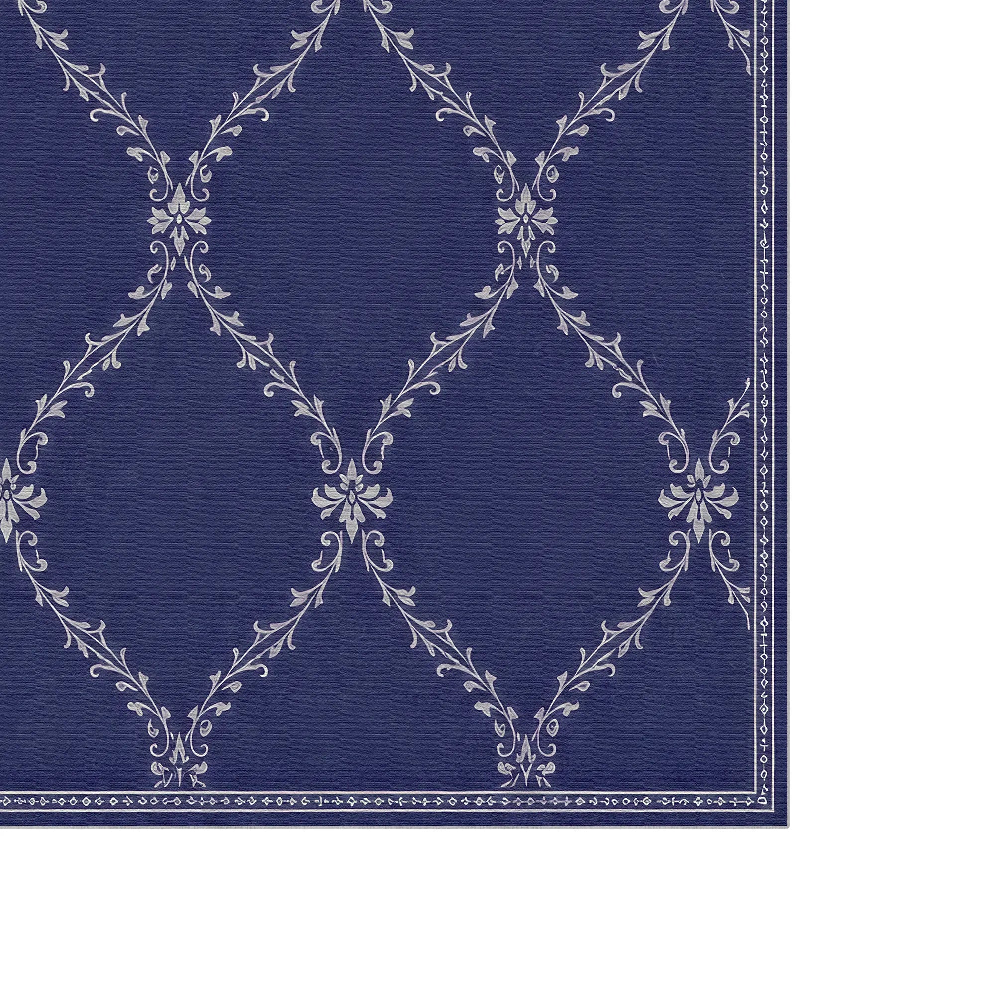 A close-up of a blue lattice rug with a repeating white damask-style floral pattern and a decorative border along the right and bottom edges.