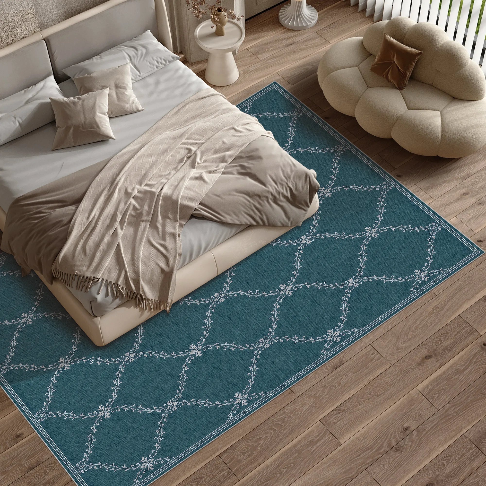 A teal blue lattice area rug with a white geometric lattice pattern is styled in a modern bedroom setting, surrounding a bed with beige linens and a cream cloud-shaped pouf on light wood flooring.