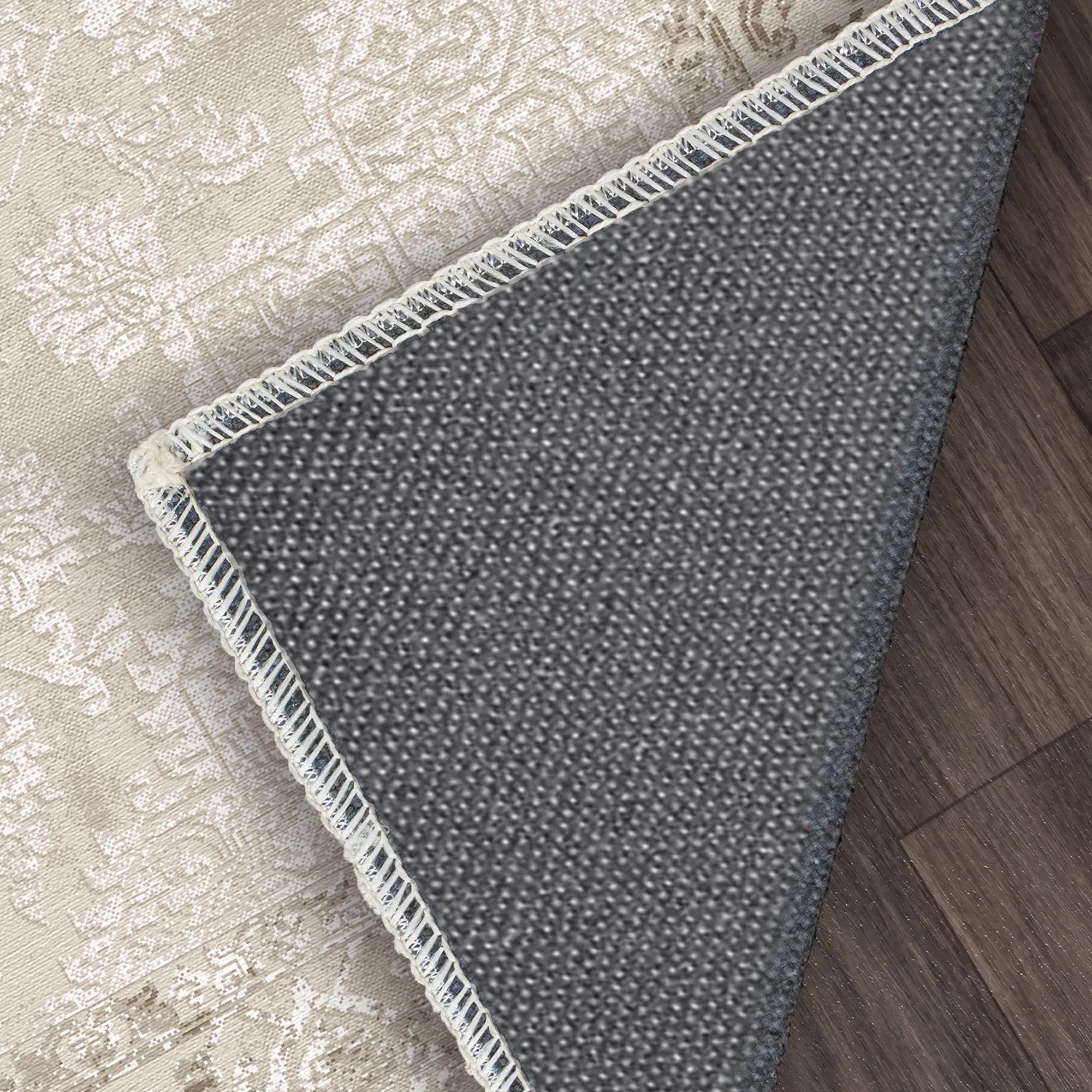 Gray textured rug with white fringe on a wooden floor